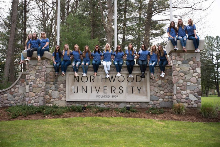 Students sitting on the NU sign