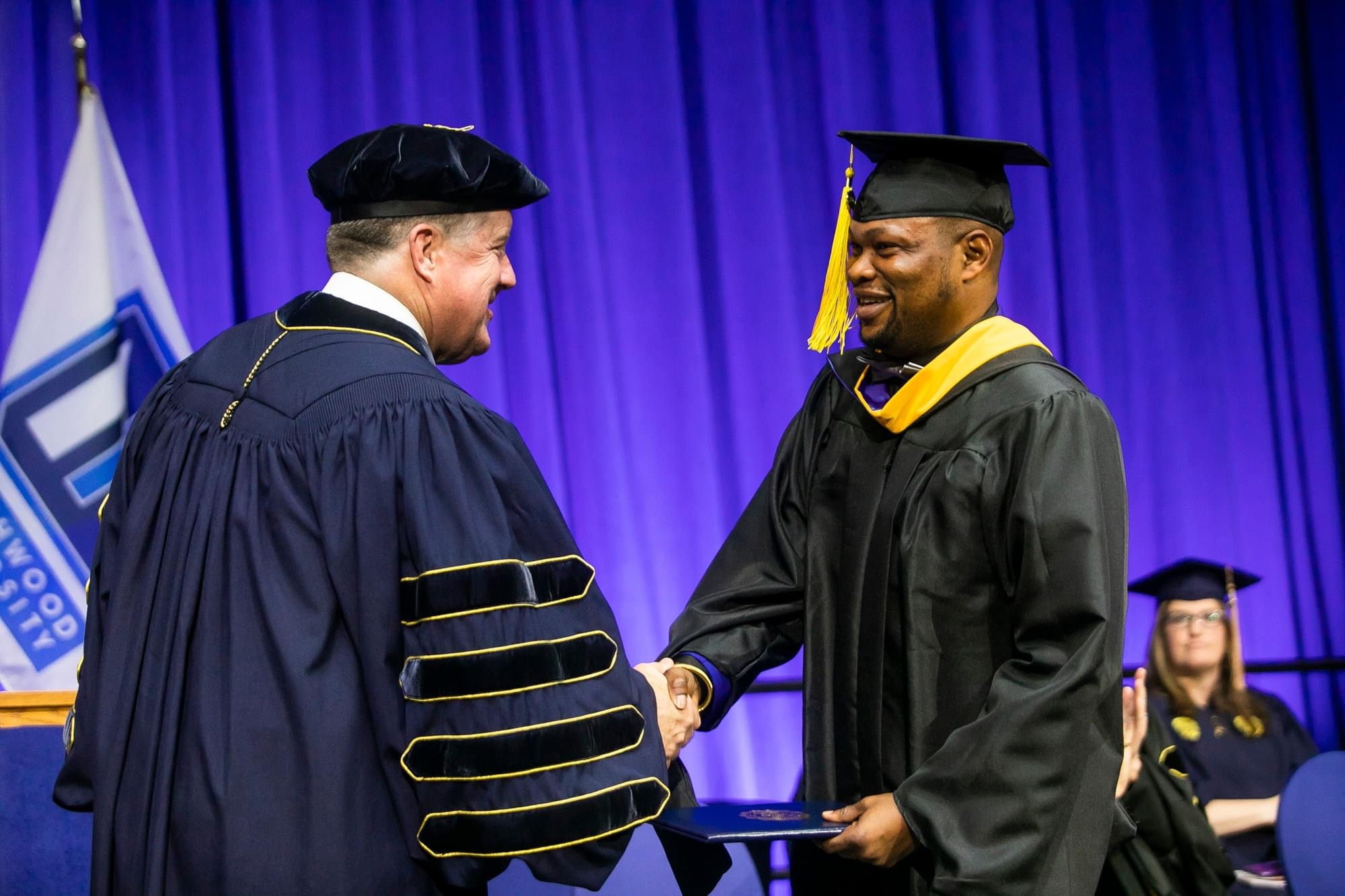 International student shaking hands with the President after receiving his diploma