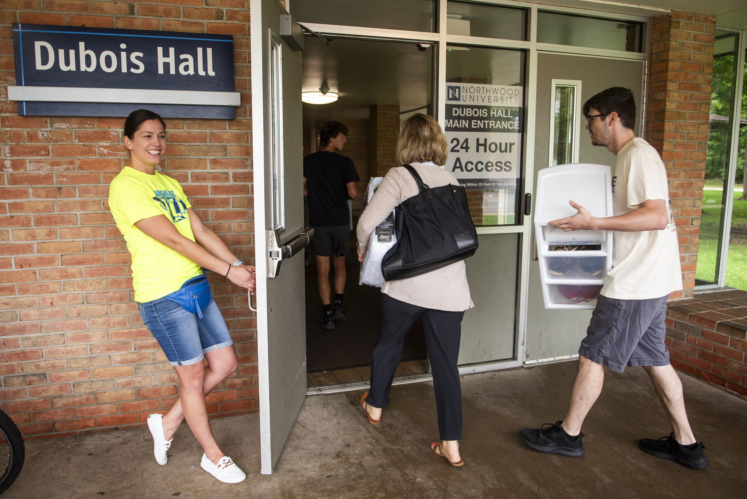 Staff member holding the door to Dubois Hall open for a student