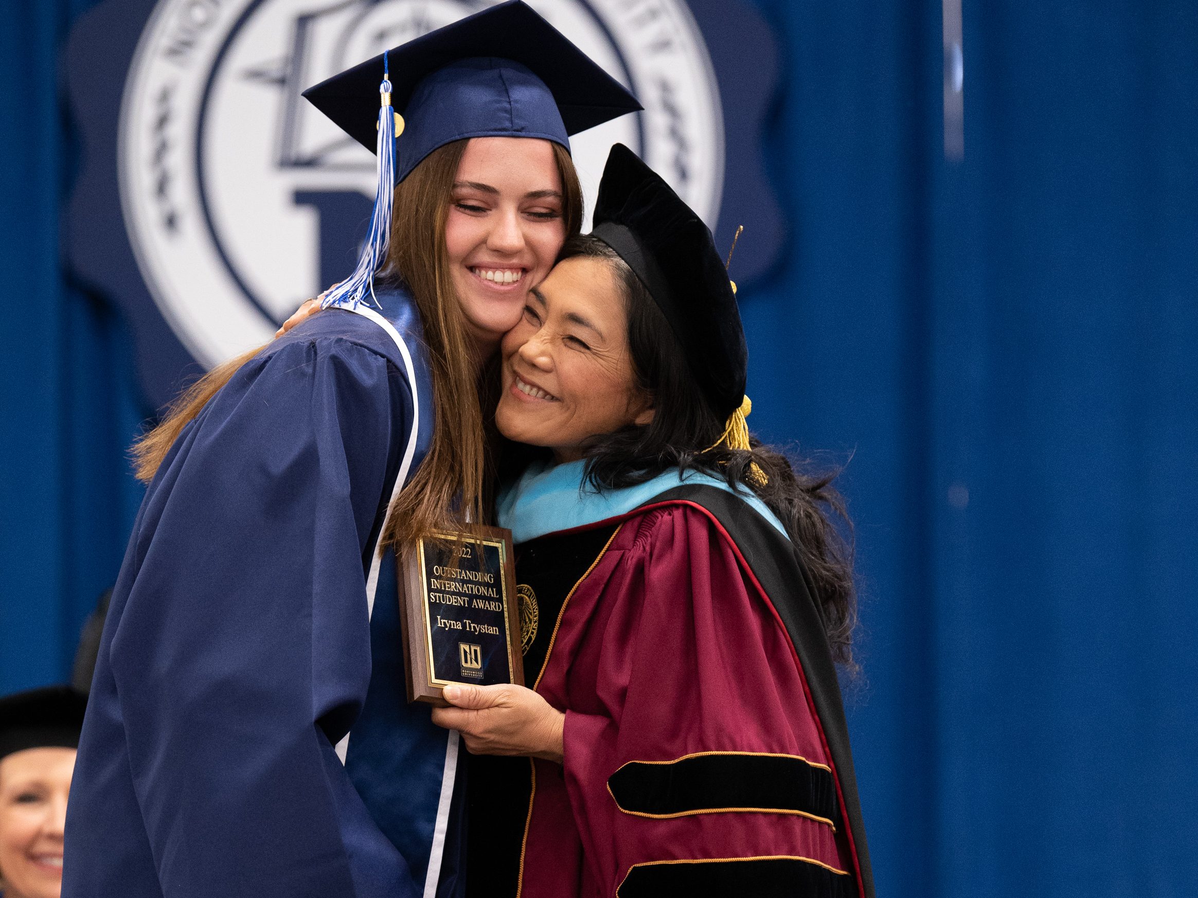 Honors student and faculty advisor embracing on stage