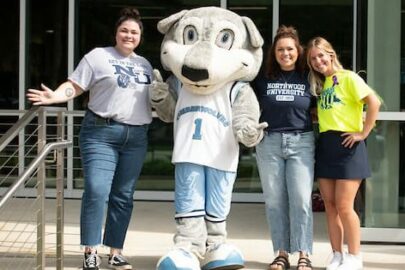 Northwood students and staff pictured with Woody the Timberwolf on the stairs of the DeVos Graduate School