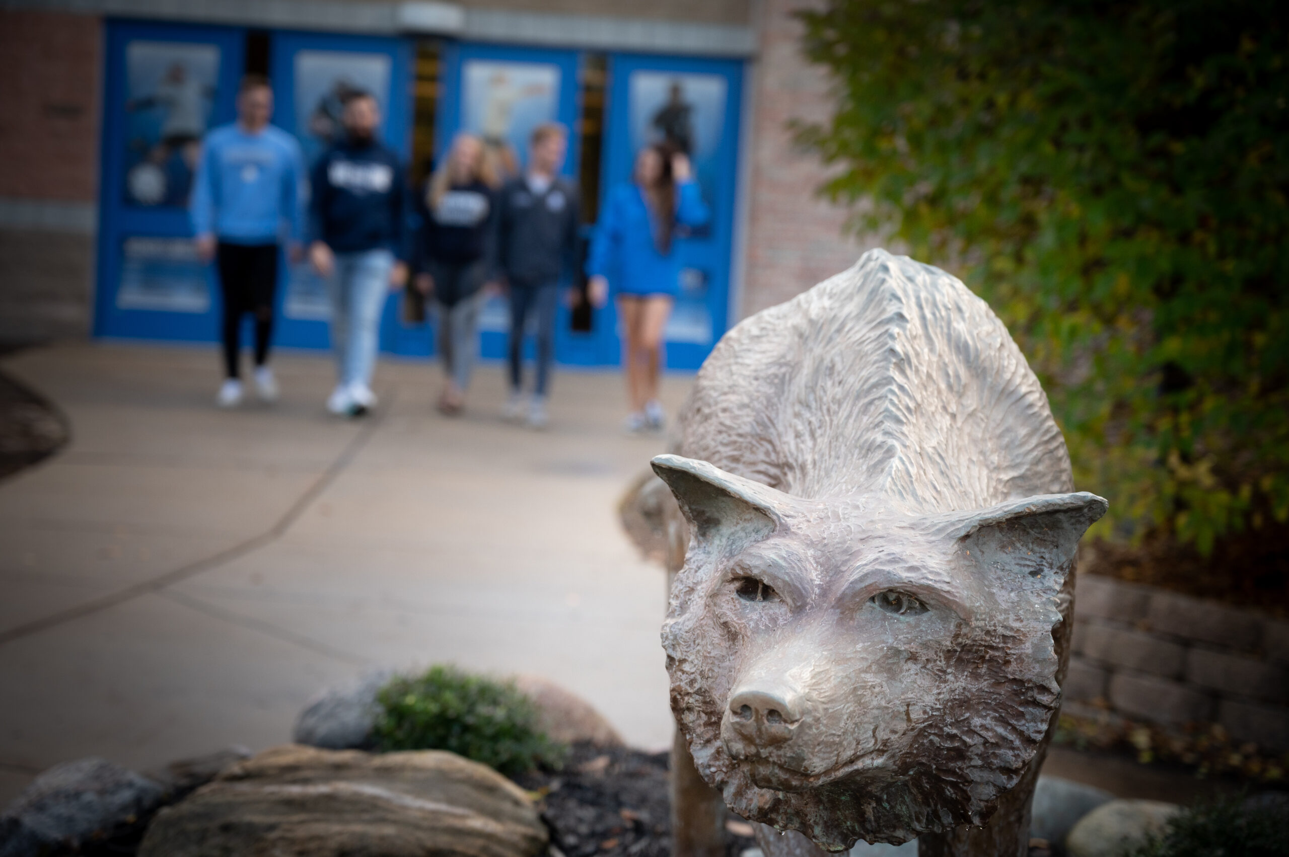 Students walking out of the Hach Center with the wolf statue in the forefront