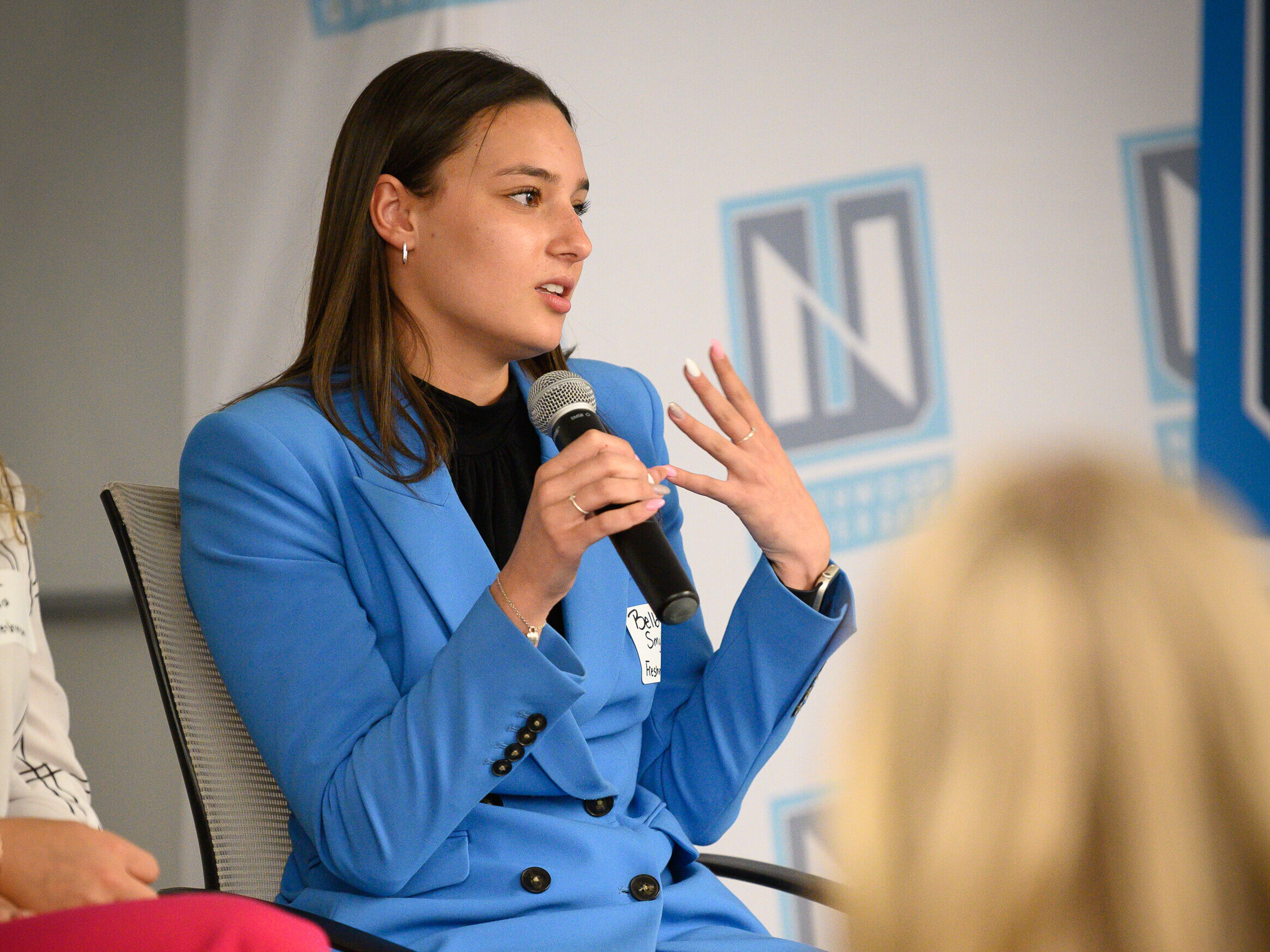Northwood student in a blue suit speaking into a microphone at an event