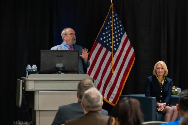 Dr. Todd Thomas and Dr. Kristin Steuhower presenting on stage with an American flag in the background